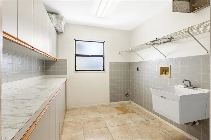 Laundry Rm. with light tile patterned flooring, hookup for a washing machine, hookup for an electric dryer, cabinet space, and tile walls