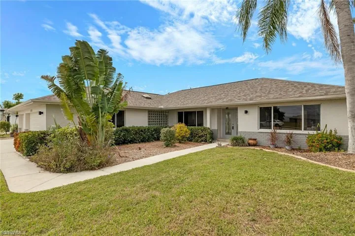 Ranch-style home with stucco siding, a front yard, and a garage