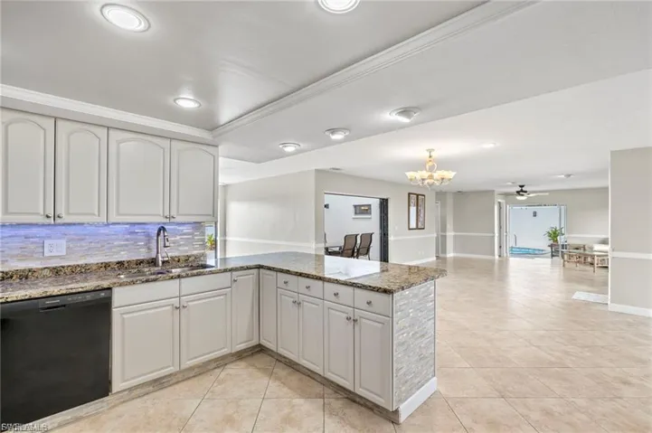 Kitchen featuring dark stone countertops, dishwasher, light tile patterned floors, backsplash, and recessed lighting