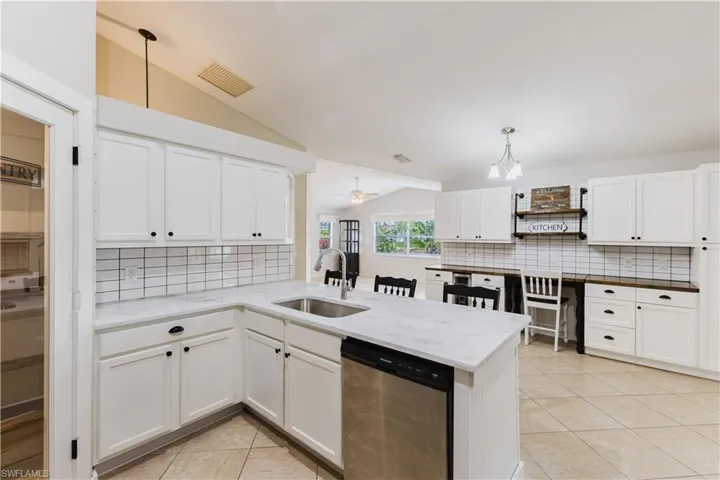 Kitchen with lofted ceiling, decorative backsplash, dishwasher, light tile patterned flooring, and white cabinetry