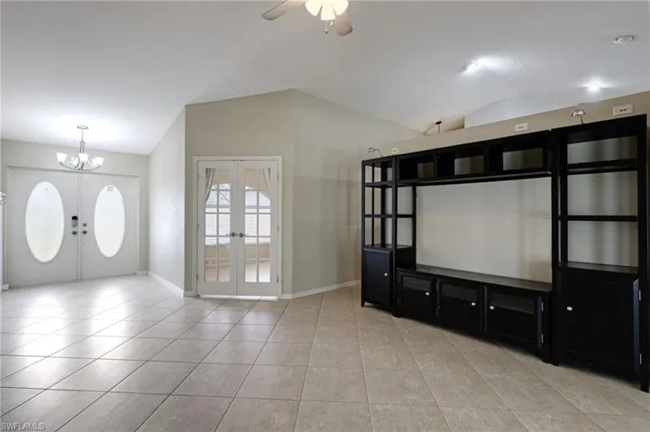 Entrance foyer with french doors, vaulted ceiling, ceiling fan, a chandelier, and light tile patterned floors