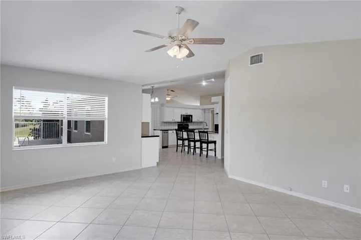 Unfurnished room with ceiling fan, light tile patterned floors, and lofted ceiling