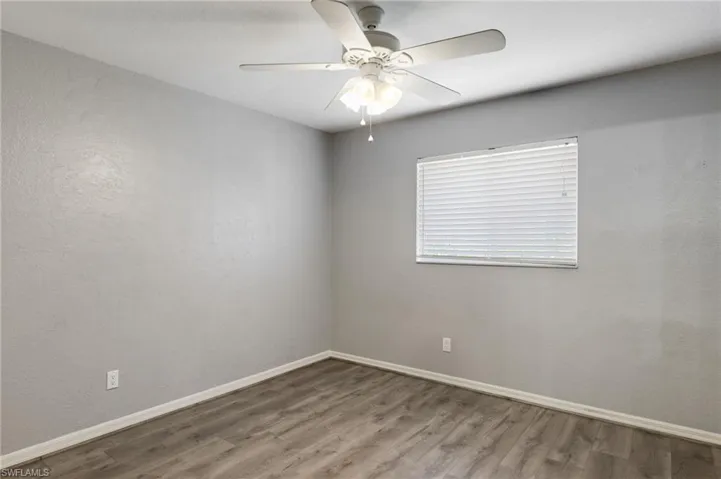 Unfurnished room with a ceiling fan, wood finished floors, and a textured wall