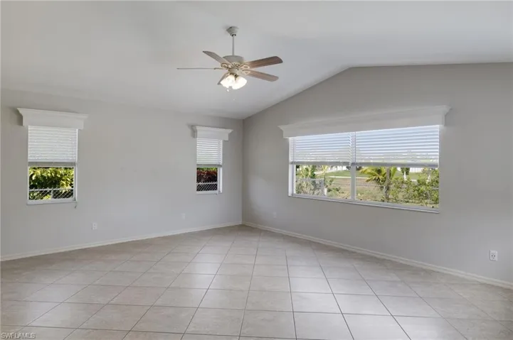 Spare room featuring a ceiling fan, lofted ceiling, and light tile patterned flooring