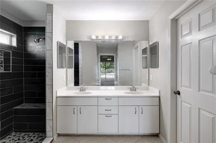 Bathroom with plenty of natural light, double vanity, and tiled shower