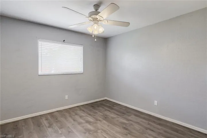 Empty room featuring wood finished floors, ceiling fan, and a textured wall