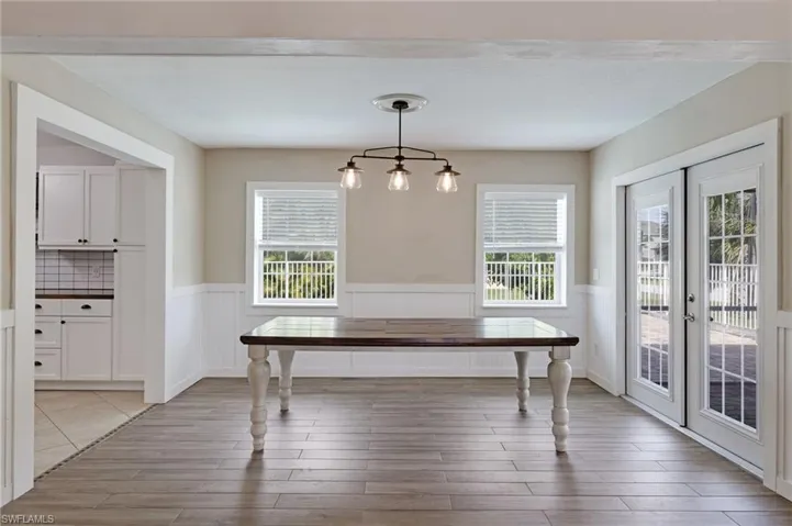 Dining area with french doors, a wainscoted wall, and light wood-type flooring