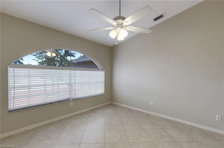 Empty room featuring vaulted ceiling, a ceiling fan, and light tile patterned floors