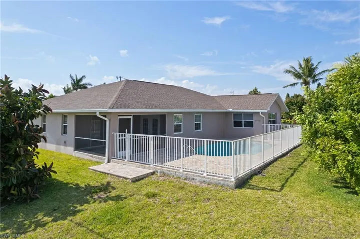 Rear view of property featuring roof with shingles, a patio area, stucco siding, and a yard