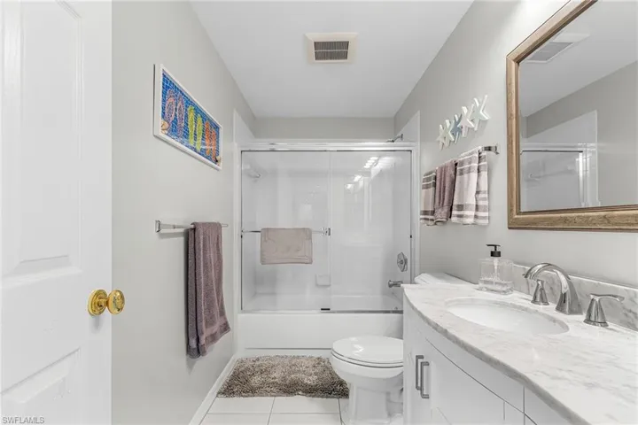 Full bathroom featuring shower / bath combination with glass door, vanity, and tile patterned floors