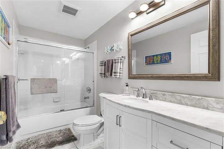 Bathroom with enclosed tub / shower combo, vanity, and tile patterned flooring