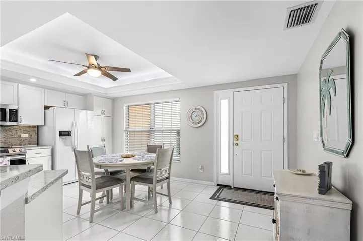Dining room featuring a raised ceiling, light tile patterned floors, and ceiling fan