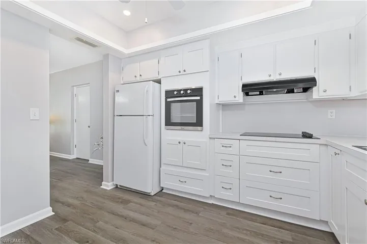 Kitchen with light wood-type flooring, light countertops, white cabinets, dishwasher, and a ceiling fan