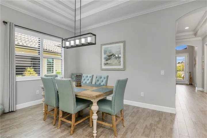 Open & Spacious dining space with new lighting fixture, tray ceilings with crown molding, and plantation shutters.