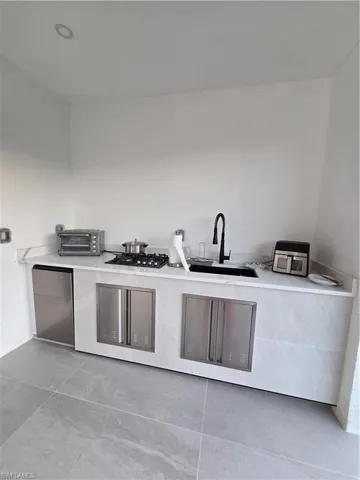 Kitchen featuring refrigerator, light stone counters, cooktop, and modern cabinets