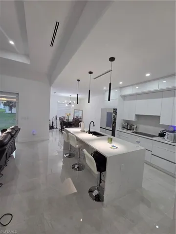 Kitchen with modern cabinets, white cabinets, open floor plan, and a breakfast bar