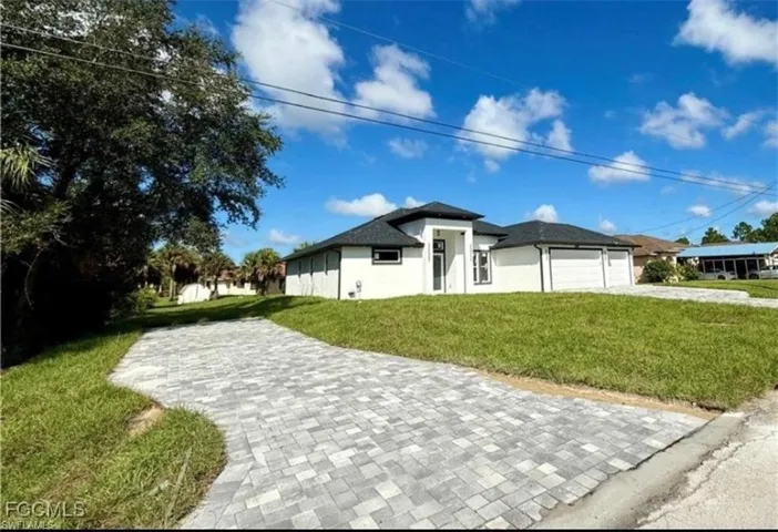 View of front of home with a front yard, stucco siding, a garage, and driveway