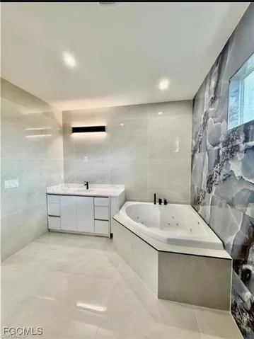 Bathroom featuring tile walls, vanity, and a whirlpool tub