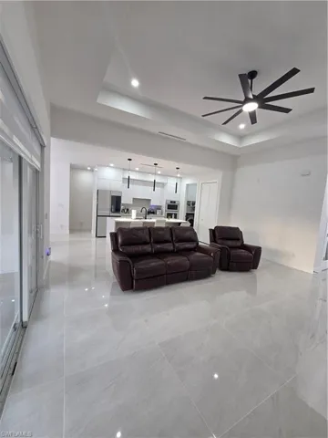 Living room featuring a tray ceiling, ceiling fan, and recessed lighting