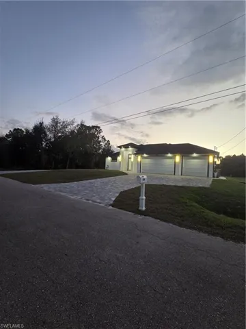View of front facade featuring a detached garage, a front yard, driveway, and an outdoor structure