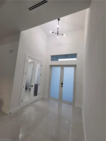 Foyer with french doors, a high ceiling, and hanging lights