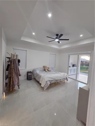 Bedroom with access to outside, a raised ceiling, recessed lighting, and ceiling fan
