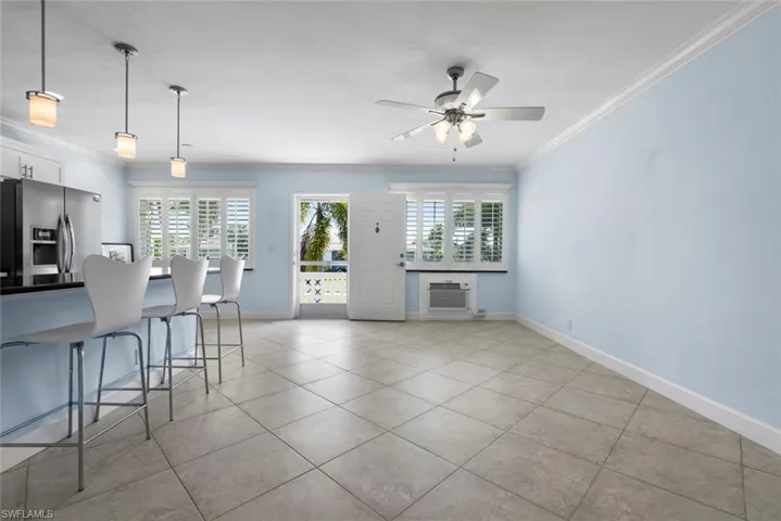 Kitchen with white cabinets, a kitchen bar, decorative light fixtures, crown molding, and stainless steel fridge