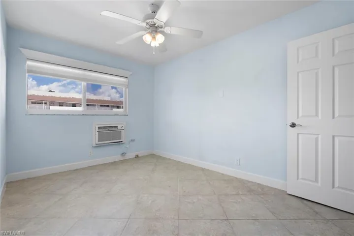 Unfurnished room featuring an AC wall unit and ceiling fan