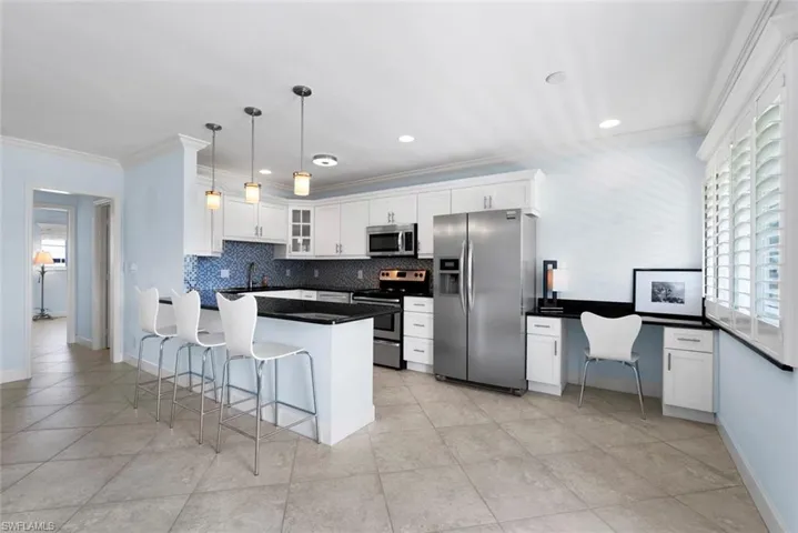Kitchen featuring appliances with stainless steel finishes, white cabinetry, a breakfast bar, tasteful backsplash, and decorative light fixtures