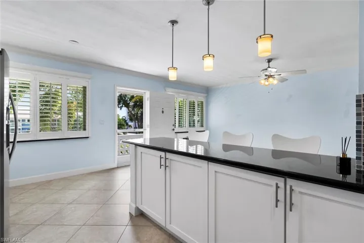 Kitchen with white cabinetry, light tile patterned floors, decorative light fixtures, ornamental molding, and ceiling fan