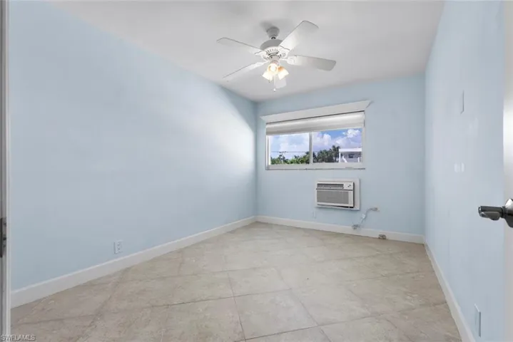 Unfurnished room with a wall unit AC and ceiling fan