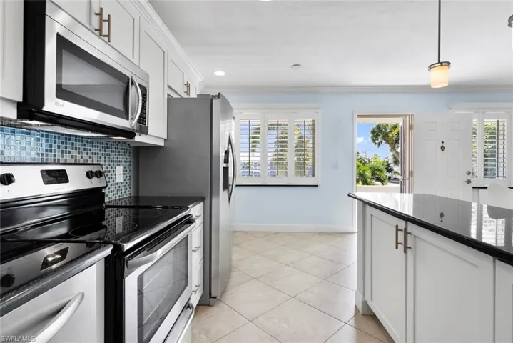 Kitchen with backsplash, plenty of natural light, stainless steel appliances, and white cabinets