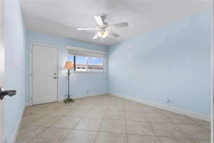 Empty bedroom featuring light tile patterned flooring and ceiling fan and rear door access