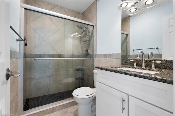 Bathroom featuring vanity, toilet, and a shower with door