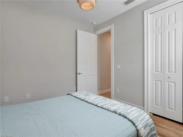 Neutral-toned room featuring wood-finish flooring, a white paneled door, and bi-fold closet doors