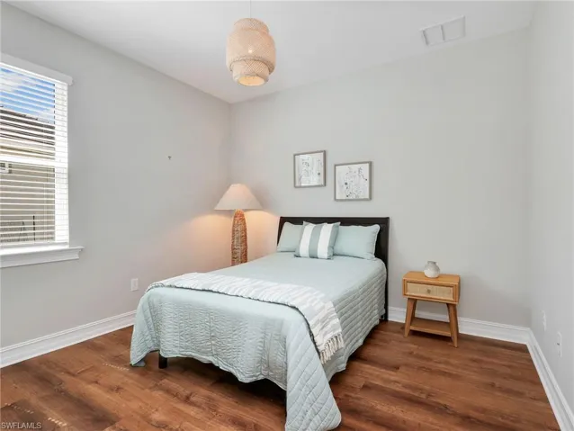 Room featuring wood-finish flooring, a contemporary woven pendant light fixture, and a single window with blinds