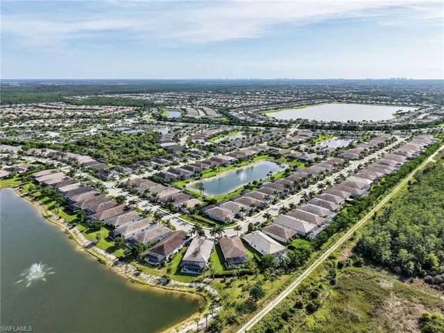 Aerial perspective of a residential community featuring numerous single-story homes, multiple lakes, and extensive green spaces