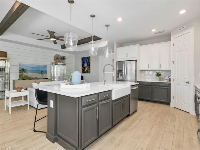 Kitchen island featuring a farmhouse sink, quartz countertop, and pendant lighting