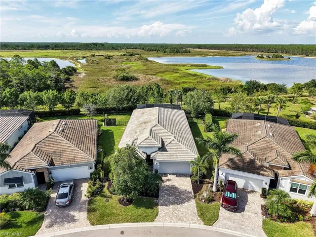 Coastal-style residence featuring a tile roof, paver driveway, and a two-car garage