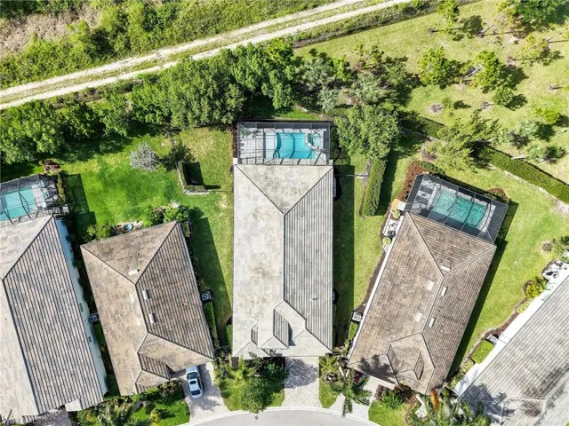 Aerial perspective showcasing a property featuring a screened-in swimming pool and a tile roof
