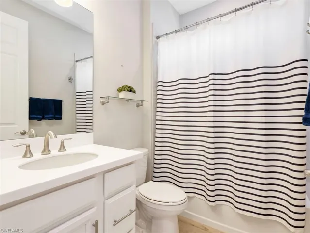 Bathroom featuring a white vanity with an integrated sink, brushed nickel faucet, and a large wall-mounted mirror