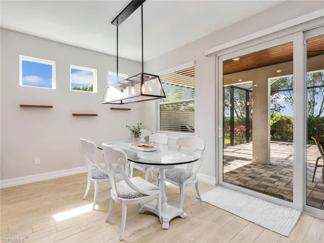 Dining area featuring light wood-finish flooring, a contemporary linear chandelier, and three high wall windows