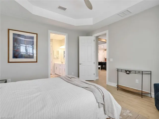 Bedroom featuring a tray ceiling with recessed lighting, wood-finish flooring, and light gray wall paint