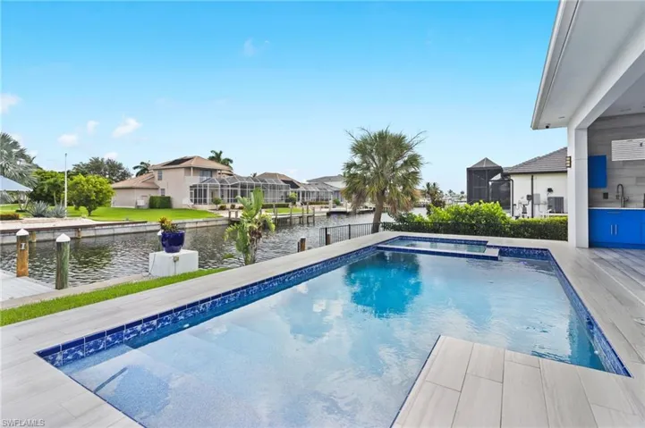 View of pool featuring glass enclosure, a water view, and sink
