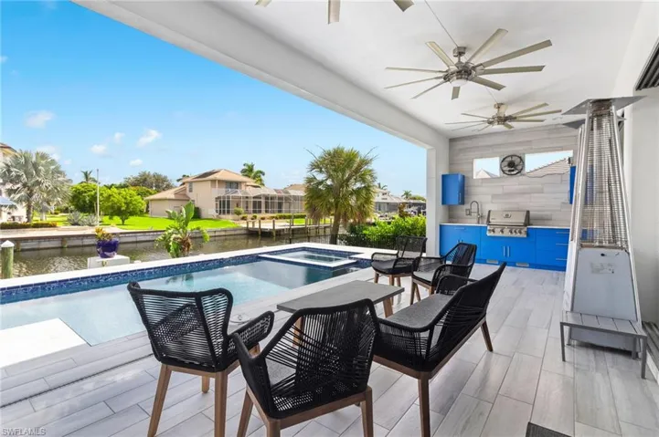 View of swimming pool featuring an in ground hot tub, a water view, ceiling fan, and a patio area
