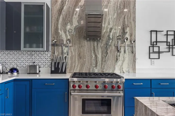 Kitchen with decorative backsplash, blue cabinets, and premium stove