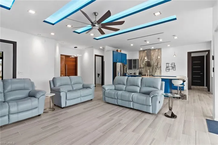 Living room with ceiling fan, a skylight, and light wood-type flooring