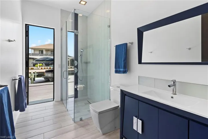 Bathroom featuring hardwood / wood-style floors, vanity, a shower with shower door, and toilet