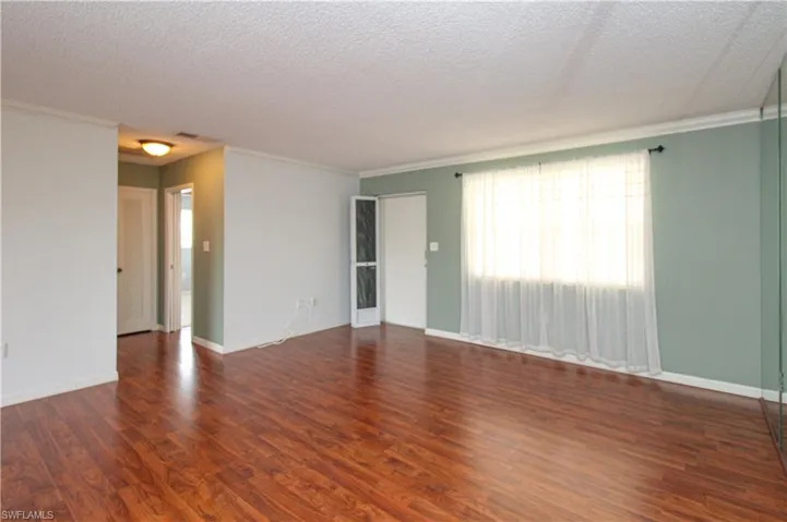 Unfurnished room featuring crown molding, dark hardwood / wood-style flooring, and a textured ceiling