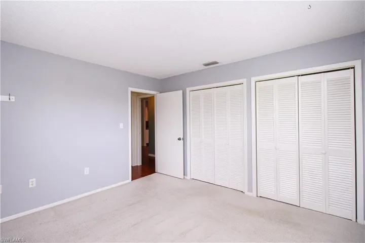 Unfurnished bedroom with multiple closets and carpet floors